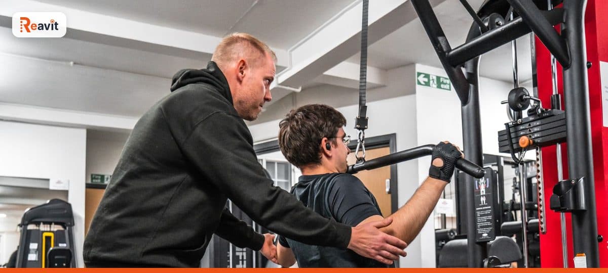 Personal trainer orientando aluno durante exercício em máquina na academia